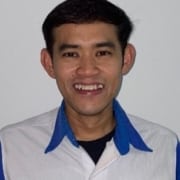 Headshot of a man smiling at the camera wearing a Cohu white and blue collared shirt in front of a white wall