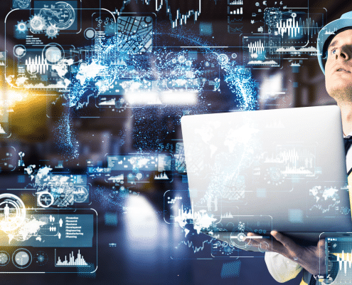 A man wearing a construction vest and hard hat holding a silver laptop and looking up. To the left of him are several transparent graphs and metrics