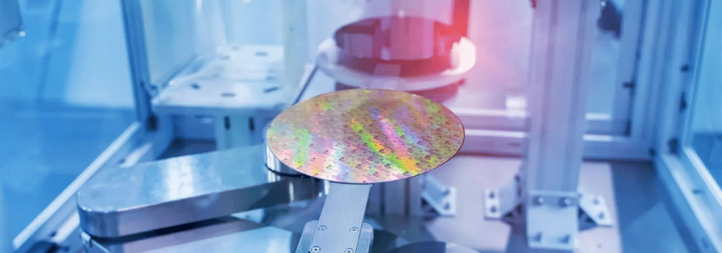 A semiconductor wafer sitting on a pedestal inside a machine with another wafer in the background