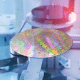 A semiconductor wafer sitting on a pedestal inside a machine with another wafer in the background